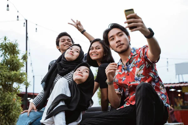 Porträt von jungen Leuten, die beim Abhängen zusammen Selfie machen — Stockfoto