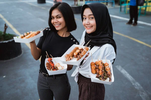 Dua wanita muda membawa makanan jalanan panggang — Stok Foto