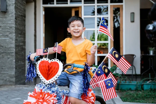 Anak mengendarai sepedanya penuh dengan bendera malaysia — Stok Foto