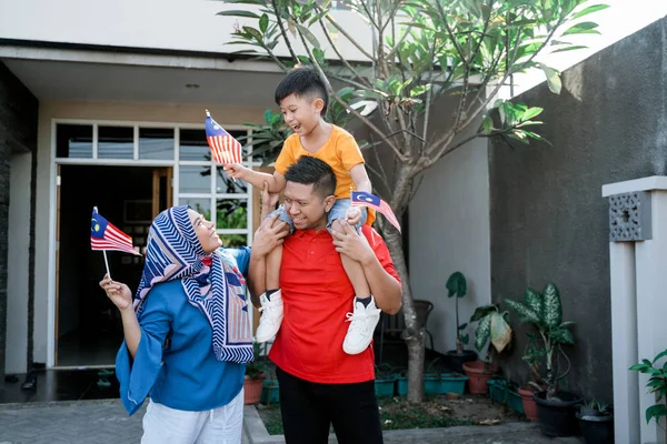 Keluarga malaysian memegang bendera malaysia di depan rumah mereka — Stok Foto