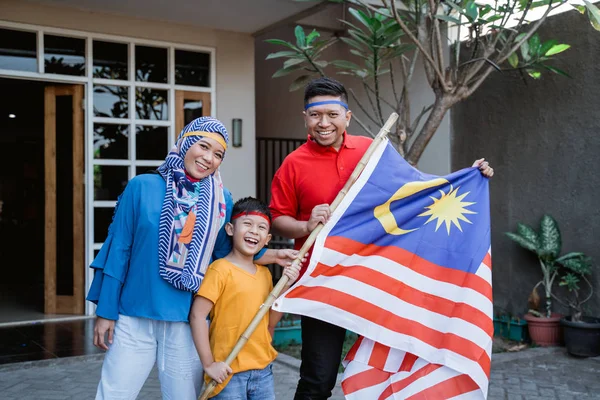Família malaia segurando bandeira malaia na frente de sua casa — Fotografia de Stock