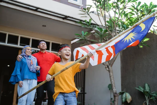 Família malaia segurando bandeira malaia na frente de sua casa — Fotografia de Stock