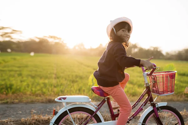 Счастливая девочка катается на велосипеде под открытым небом — стоковое фото