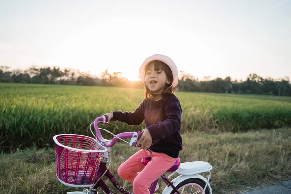 Счастливая девочка катается на велосипеде под открытым небом — стоковое фото