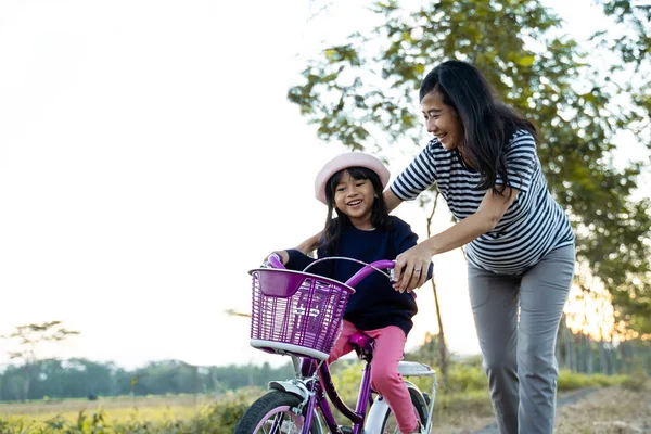 Mamá enseñar a su hija pequeña a aprender bicicleta — Foto de Stock