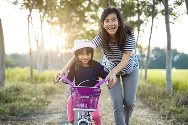 Moeder leert haar peuter dochter om te leren fiets — Stockfoto