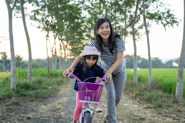 Niño aprendiendo a andar en bicicleta con la madre —  Fotos de Stock