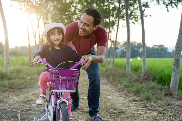 Filha aprendendo a andar de bicicleta com papai — Fotografia de Stock