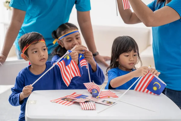 Anak-anak membuat bendera malaysian bersama-sama di rumah dengan keluarga — Stok Foto