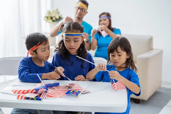 Kinderen maken Maleisische vlaggen samen thuis met familie — Stockfoto