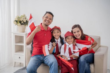 Endonezyalı aile beyaz arka plan üzerinde Endonezya bayrağı tutarak