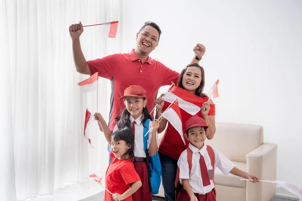 Keluarga bahagia dengan bendera indonesia mengangkat lengan mereka — Stok Foto