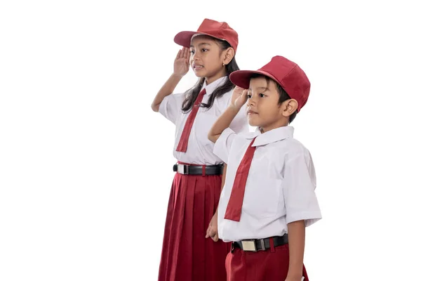 Studente elementare indossa uniforme dando il saluto alla bandiera indonesia — Foto Stock