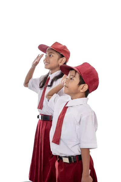 Elementaire student draagt uniform geven groet aan de vlag van Indonesië — Stockfoto