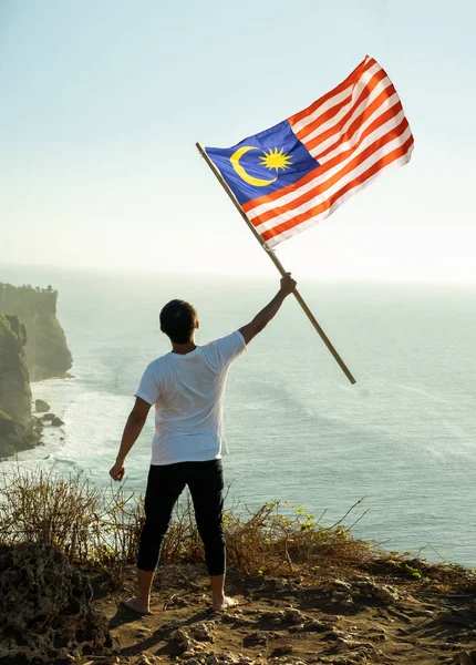 Uomo con bandiera malese della Malesia in cima alla montagna — Foto Stock