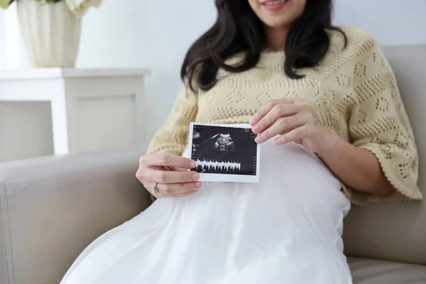 Обрезанное изображение беременной азиатки с ультразвуковым сканированием — стоковое фото