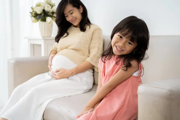 Asiatisches kleines Mädchen lächelt, wenn es auf dem Sofa sitzt — Stockfoto