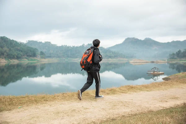 湖の景色を見下ろすバックパックを持つ旅行者 — ストック写真
