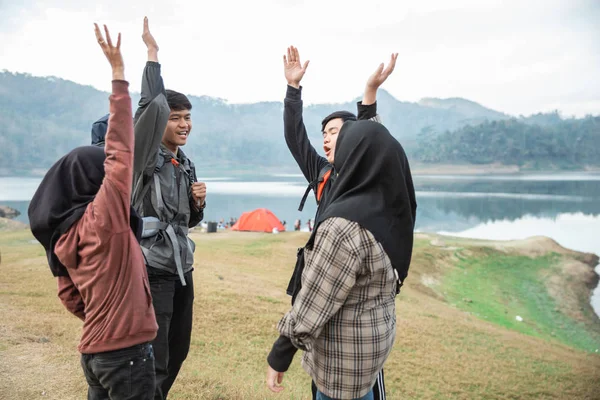 Gruppo di amici incontro e alzare la mano godere di vista sul lago — Foto Stock