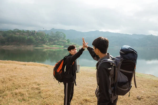 Dois asiáticos viajantes com brinde em pé perto do lago — Fotografia de Stock