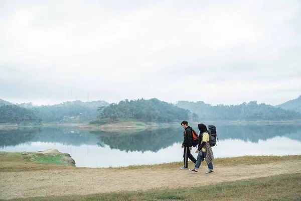 Par vandrare med ryggsäckar Walking Side sjön — Stockfoto