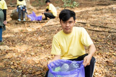 asyalı adam gönüllü aşağı çömelmek zaman çöp torbası tutarak