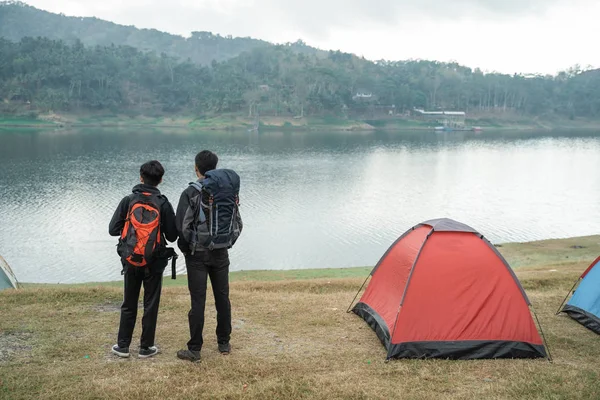 Dos viajeros asiáticos de pie cerca del lago —  Fotos de Stock