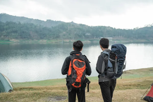 Dos viajeros asiáticos de pie cerca del lago —  Fotos de Stock