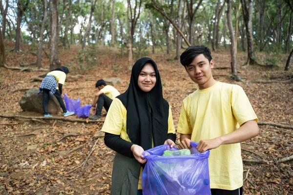 Pasangan Muslim tersenyum relawan memegang kantong sampah — Stok Foto