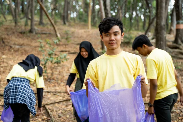 Pria tersenyum sukarela memegang kantong sampah — Stok Foto