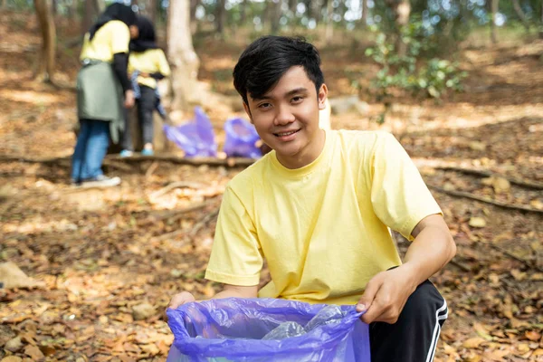 Pemuda Asia tersenyum sukarela memegang kantong sampah — Stok Foto