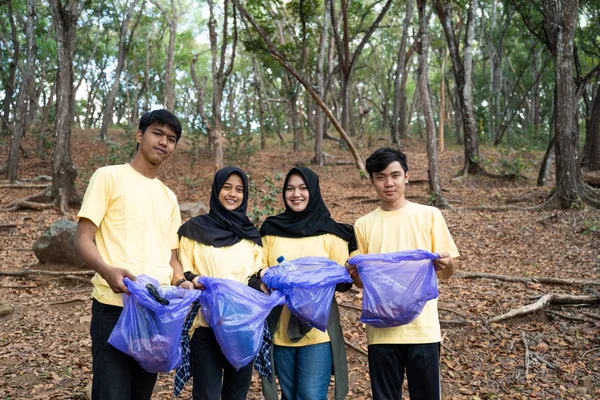 Sekelompok relawan yang tersenyum memegang kantong sampah — Stok Foto