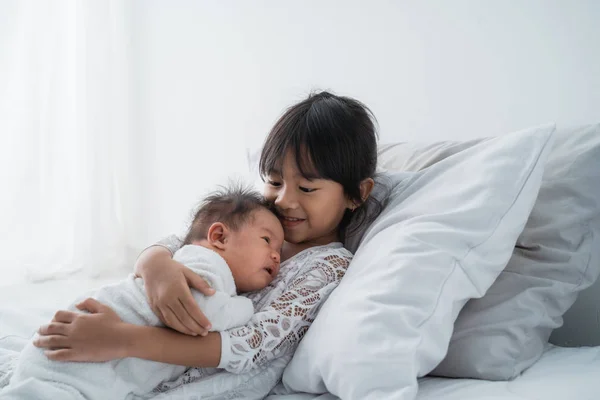 Дочка дитина з немовлям сестра грає на ліжку в білому — стокове фото