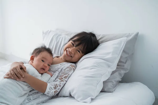 Sonriente feliz chica hermano bebé acostado en la cama — Foto de Stock
