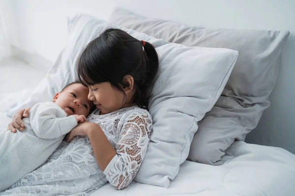 Sonriente feliz chica hermano bebé acostado en la cama — Foto de Stock