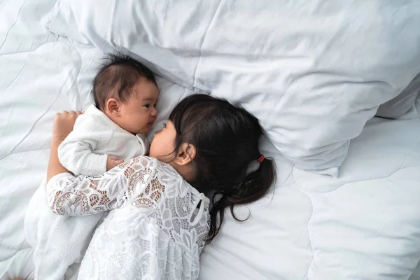 Hija niño con bebé hermano jugando en la cama vistiendo blanco — Foto de Stock