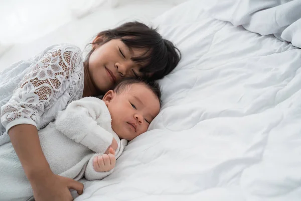 Hija niño con bebé hermano jugando en la cama vistiendo blanco —  Fotos de Stock