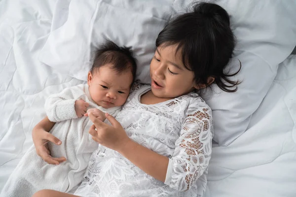 Улыбаясь счастливая девочка брат и сестра младенца лежит на кровати — стоковое фото