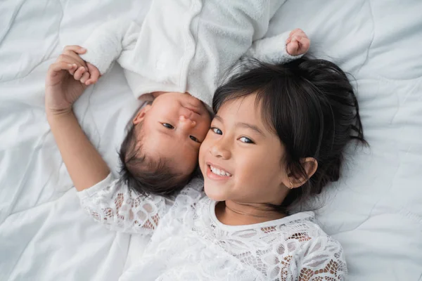 Sonriente feliz chica hermano bebé acostado en la cama —  Fotos de Stock