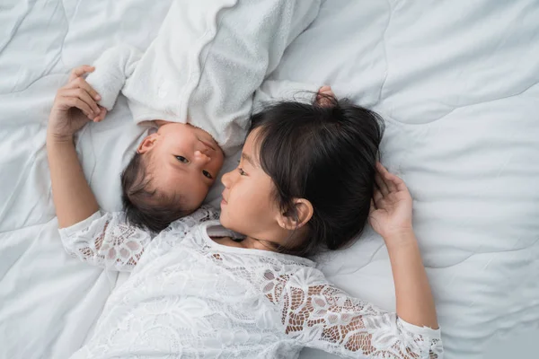 Hija niño con bebé hermano jugando en la cama vistiendo blanco — Foto de Stock