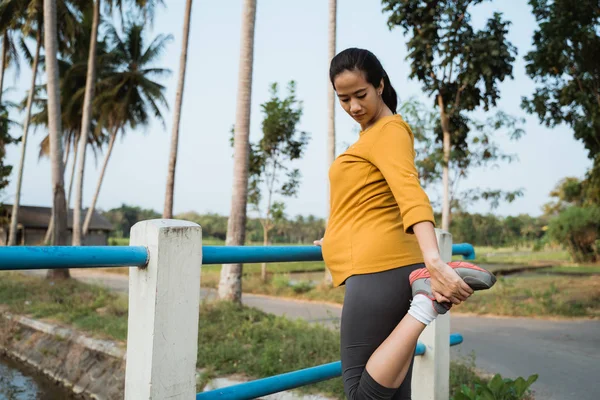 妊娠中の女性は、屋外で運動中に彼女の足を伸ばす — ストック写真