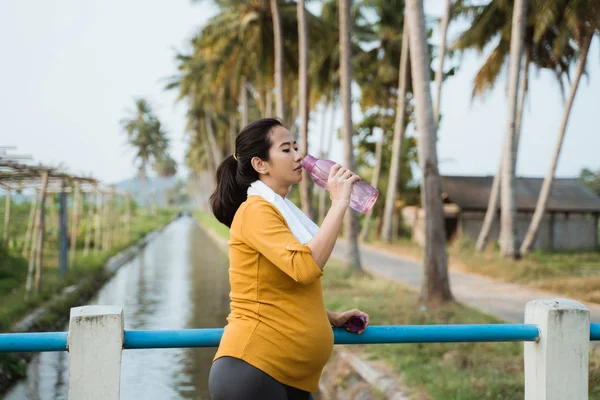 Těhotnou ženu Pijte láhev vody při cvičení — Stock fotografie