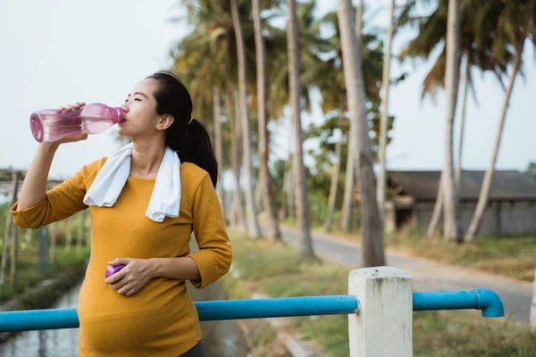 Mulher grávida beber garrafa de água durante o treino — Fotografia de Stock