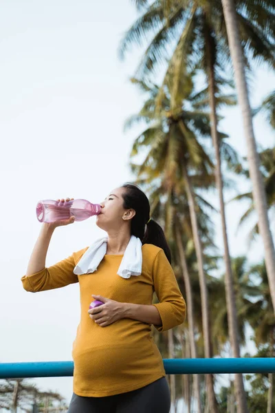 pregnant woman drink water bottle while workout