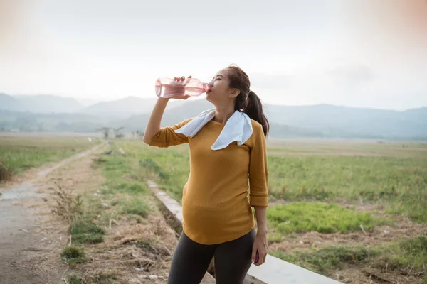 Hamile kadın egzersiz sırasında su şişesi içmek — Stok fotoğraf