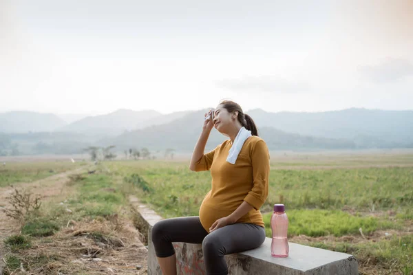 Hamile kadın açık havada koşu sırasında oturup — Stok fotoğraf