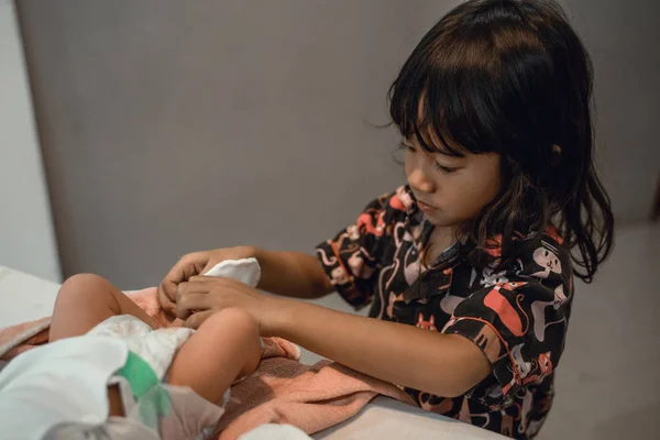 Niña ayudando a la madre a cambiar el pañal de su bebé recién nacido — Foto de Stock