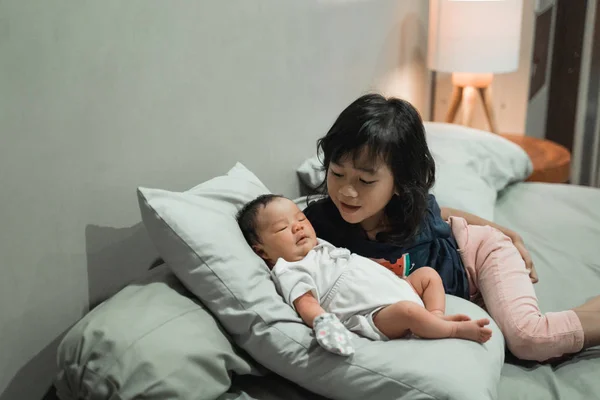 Soeur aînée jouant avec petite soeur sur le lit — Photo