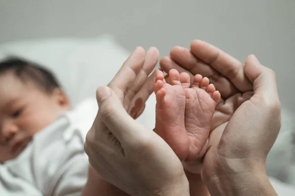 Mor händer som håller baby fötter — Stockfoto