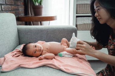 asyalı anne küçük kızına bebek bezi uygulayarak